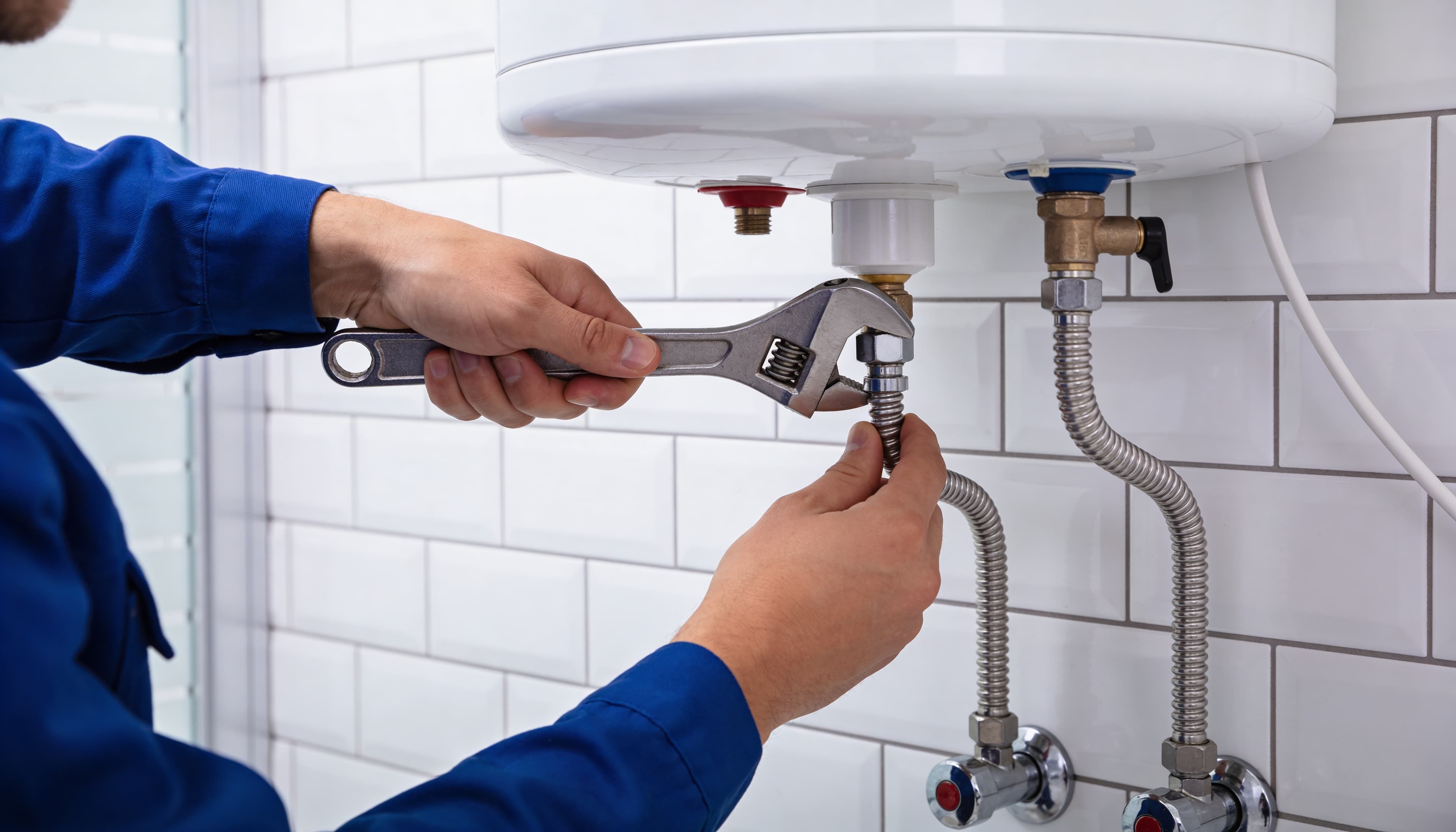 Noohi technician installing residential water heater connections with adjustable wrench